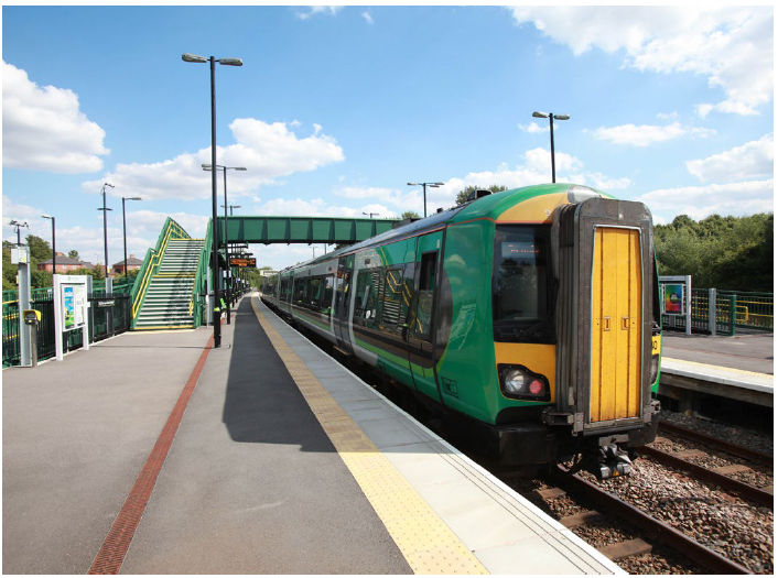 image of a green and yellow train stopped at a station. 