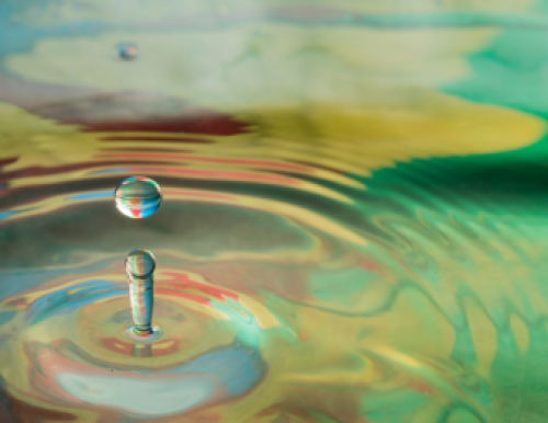 Photograph of a water droplet making ripples in a pool of water