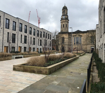 A photo showing town houses creating a square and framing the view of a church